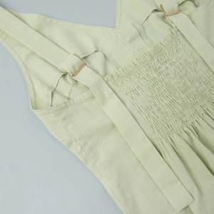 Detail of sage green cotton top featuring adjustable straps and elastic smocked back design