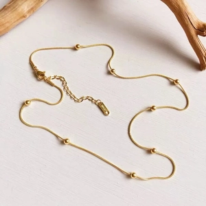 Detailopname van de 18K vergulde karabijnsluiting en 18KGP gravure op de slangenketting