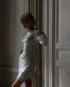 Détail de paillettes argentées scintillantes sur une robe courte ajustée à manches
