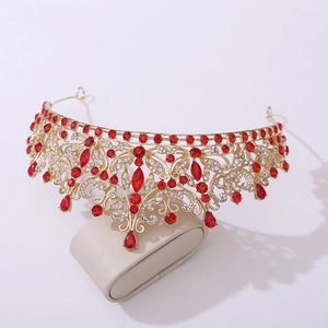 Macro view of gold bridal crown featuring intricate leaf patterns and red drop gemstones