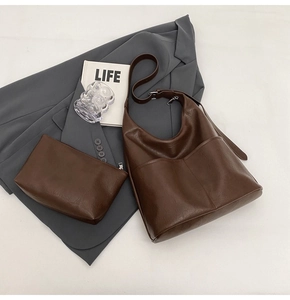 Flat lay of dark brown leather tote bag and pouch set with professional styling