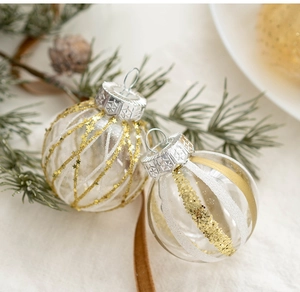 Close-up of glitter-patterned 6cm glass Christmas ornaments on soft white fabric