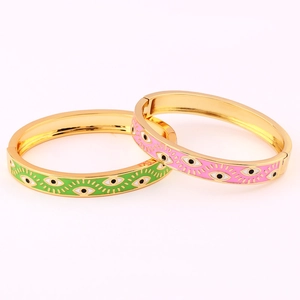 Macro detail of gold-plated enamel evil eye bangles with green and pink patterns