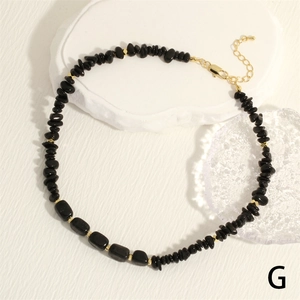 Detailed macro of black gemstone chip necklace with golden beads and lobster clasp
