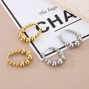 Detail of gold and silver U-shaped earrings with graduated metal beads on cards