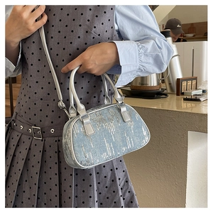 Detail einer hellblauen Denim-Handtasche mit silbernen Pailletten, getragen im Café