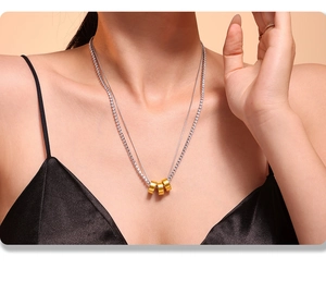 Double-layer necklace with zircon tennis chain and three golden cylinder pendants on a model
