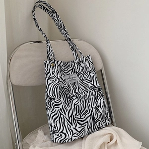 Detail of canvas tote bag featuring zebra pattern, gold clasp and Augur brand label