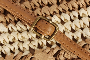 Détail de la bandoulière en cuir marron avec boucle en bronze sur sac tissé