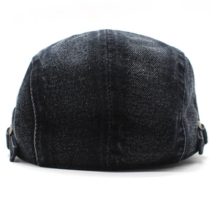 Detail of dark denim beret cap featuring adjustable metal side buckle and contrast stitching
