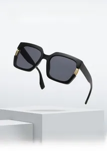 Detail of square oversized sunglasses with black frame and golden hinge hardware accents