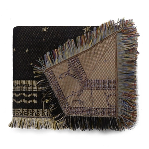 Detail of bohemian jacquard woven blanket showing golden pattern and colorful fringe