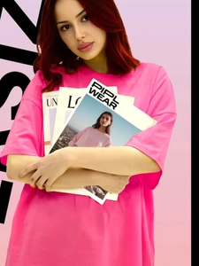 Λεπτομέρεια από ροζ βαμβακερό oversized t-shirt σε μοντέλο που κρατάει ένα περιοδικό