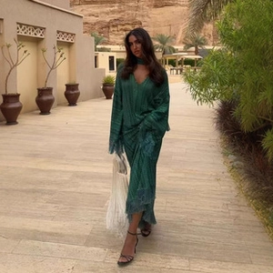 Detail of dark green bohemian dress featuring flared sleeves and fringe hem for vacation