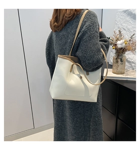 Minimalist beige tote bag featuring brown edge piping and a metallic snap button pocket