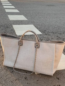 Large capacity beige canvas tote bag with brown leather handles and a metal chain strap