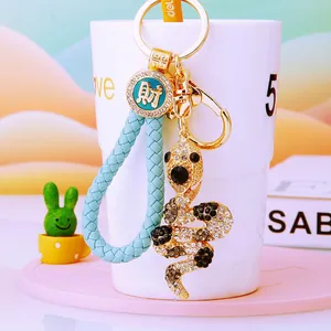 Detail view of crystal snake keychain with light blue braided strap and lucky charm