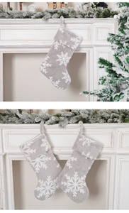 Detailed view of gray plush Christmas stocking with white snowflake prints on fireplace