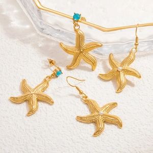 Gold starfish earrings with blue gemstone and white pearl pendants on white background