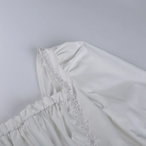 Detalle de encaje bordado blanco y manga plisada en el vestido de estilo princesa