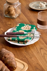 Detail of dark green Christmas napkin with gingerbread print on a white vintage plate