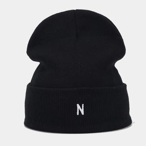 Detail of the white letter N embroidery on a black ribbed knit beanie for men and women