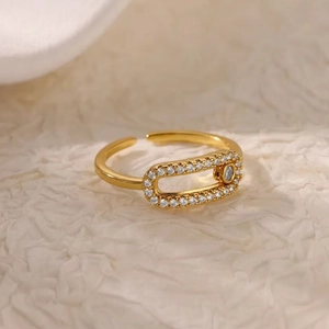 Minimalist gold U-shaped open ring with cubic zirconia paving on beige background