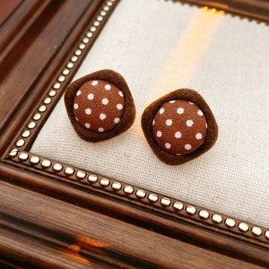 Close-up of vintage brown polka dot fabric earrings in a rhombus plush frame