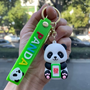 Detail of cute panda keychain holding a green mahjong tile with gold metal ring