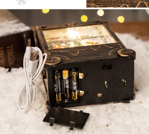 Detail showing dual power options with USB cable and battery compartment for snow globe lantern