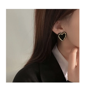 Close-up of black heart earrings with gold trim on model for a retro minimalist style
