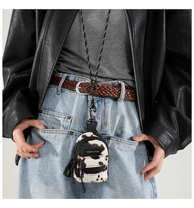 Close-up of cow print mini bag with long strap worn on a stylish black leather jacket