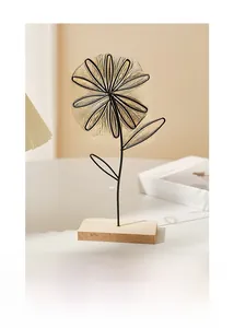 Detail of minimalist black wire flower sculpture on a rectangular wooden base for desk decor