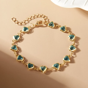 Detail of gold chain bracelet featuring blue heart-shaped stones and lobster clasp