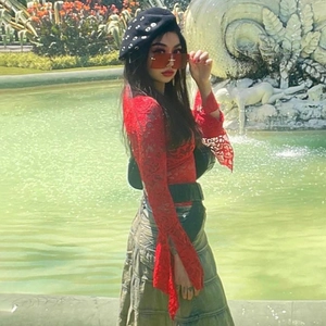 Foto di moda di una donna con top in pizzo rosso a maniche lunghe e gonna verde oliva