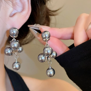 Close-up of vintage grey pearl drop earrings with silver pins on a model and hand