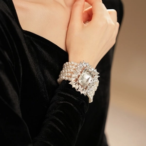 Close-up of a multi-layer pearl bracelet with a large rectangular crystal and silver floral setting