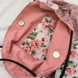Detail of pink floral lining and magnetic snap closure on a lace canvas tote bag