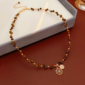 Detail of tiger eye bead necklace with gold zircon pendants on a luxury display tray