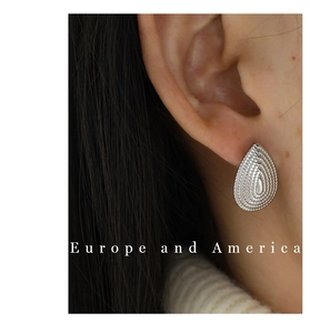 Detailed view of silver water drop stud earring with radiant texture on a female model