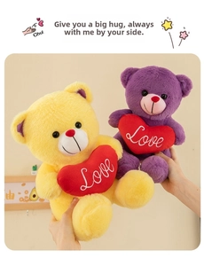 Close-up of yellow and purple plush teddy bears holding red Love heart pillows