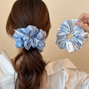 Blue and white striped scrunchie shown on hair and held in hand for a stylish look