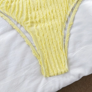 Detailed macro shot of bright yellow smocked textured fabric on high-elastic bikini bottoms