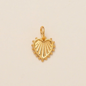 Detailed view of a golden heart pendant with radial texture and beaded edges