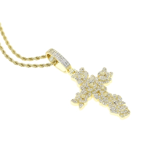 Gros plan du pendentif croix dorée serti de zircons cubiques sur chaîne torsadée