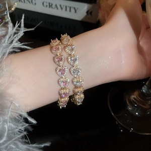 Detail of pink and white heart-shaped zircon bracelets worn together on model wrist
