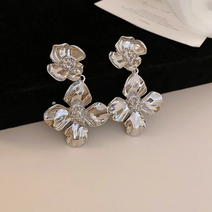 Close-up of silver flower drop earrings featuring textured petals on black velvet background