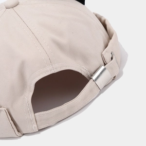 Detail of adjustable metal buckle and twill cotton strap on beige brimless docker cap