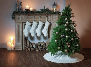 Cozy cream cable knit Christmas stockings and matching tree skirt on a fireplace mantel