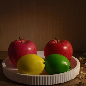 Striped resin tray with lifelike foam apple and lemon set on a dark rustic wooden table